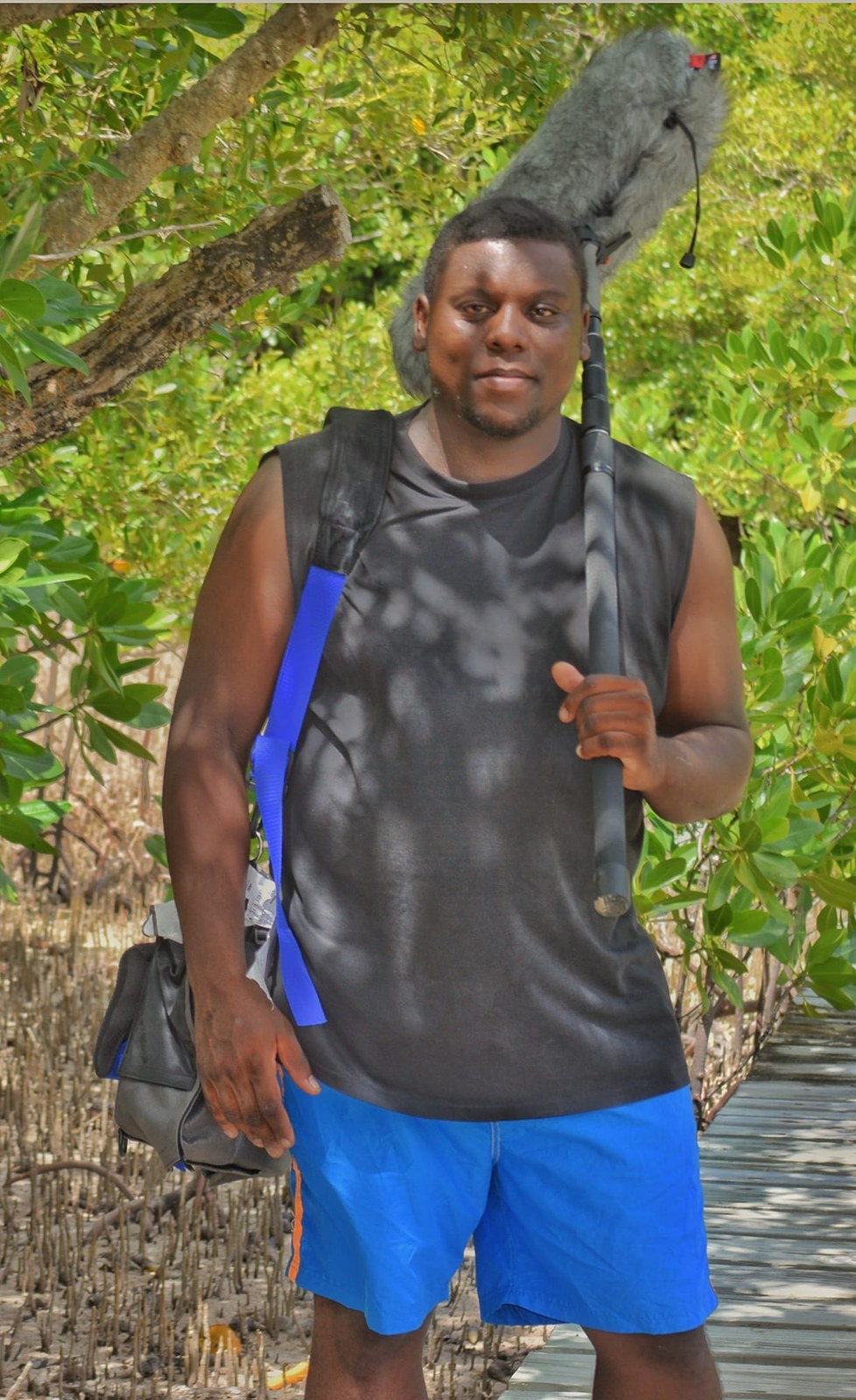 Allen carrying a boom microphone while working outdoors