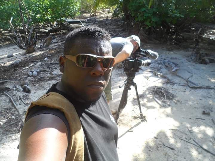 Allen beside a camera on a tripod in the mangroves